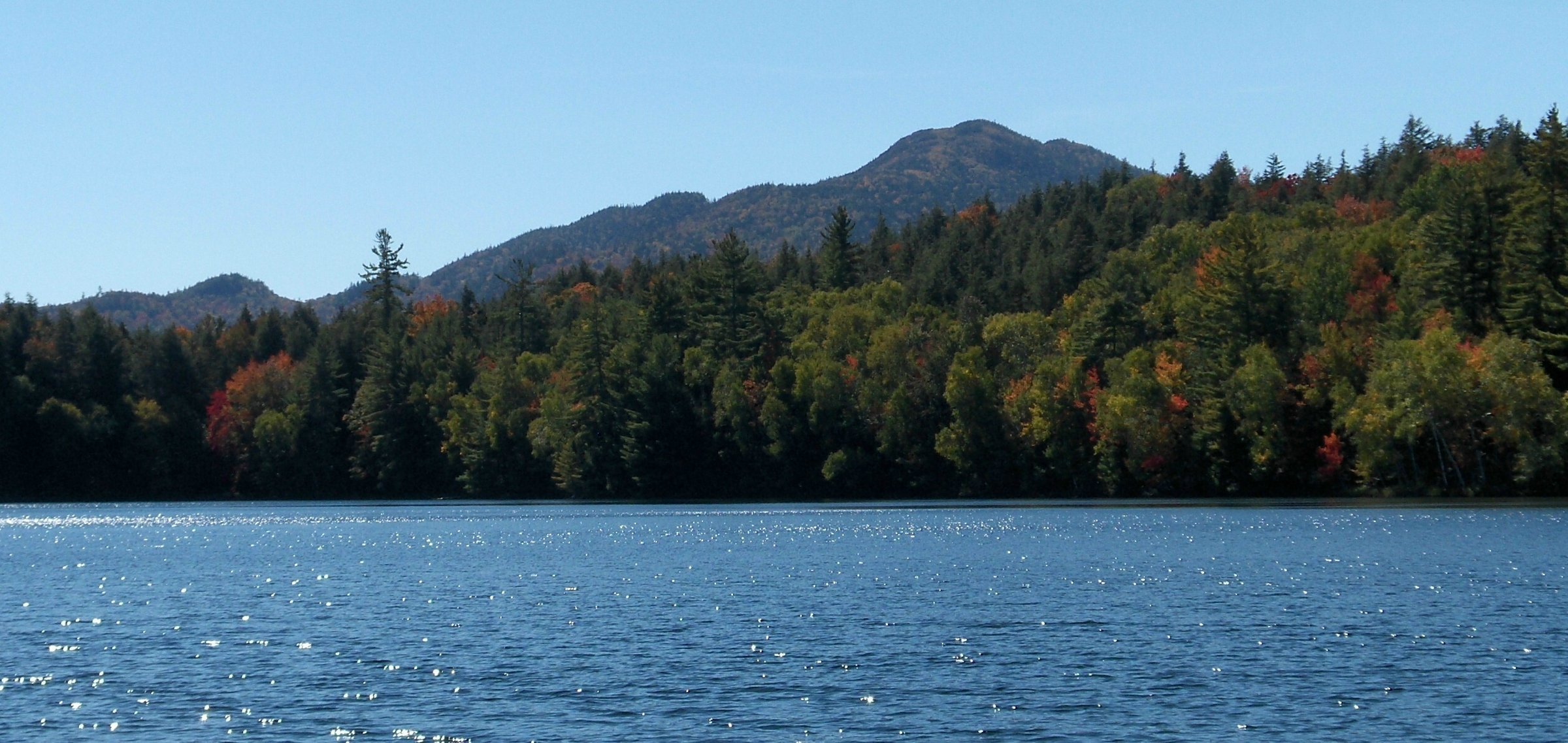 Adirondack High Peaks behind a lake with fall foliage on the shore